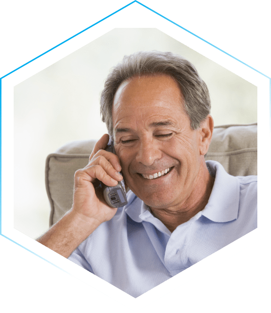 An older gentlemen smiles while talking on a wireless landline telephone