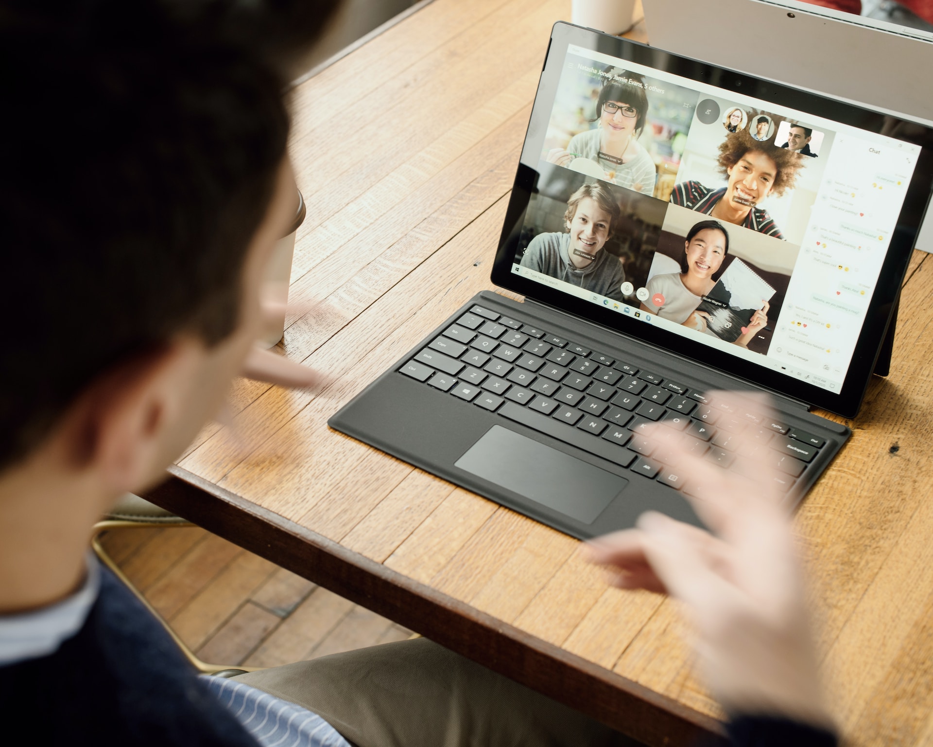 Person using an ipad to video chat with four people in a grid on the screen